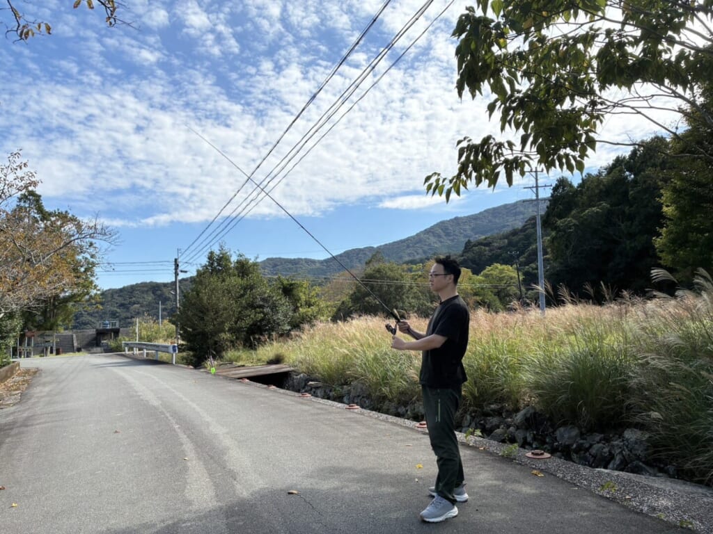 山あいの道で釣り竿を構える堀口尚志さん